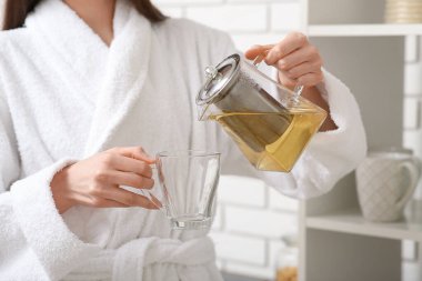 Genç kadın çaydanlıktan fincana çay dolduruyor.