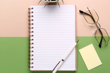 Renk arkaplanı üzerine kalem, gözlük ve defter