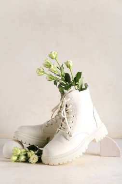 Beyaz arka planda güller olan beyaz çizmeler