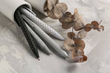 Güzel okaliptüs dallı vazo ve gri grunge arka planda kalemler.