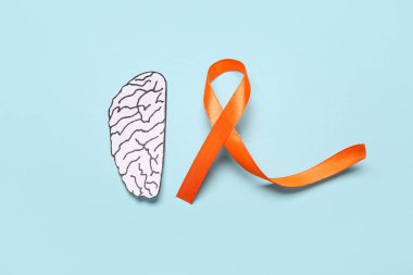 Kağıt beyin ve mavi arka planda turuncu kurdele. Çoklu Skleroz Farkındalık Ayı
