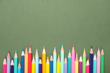 Yeşil arka planda birçok parlak renkli kalemler