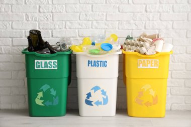 Beyaz tuğla duvarın yanında farklı çöp kutularıyla dolu. Geri dönüşüm kavramı