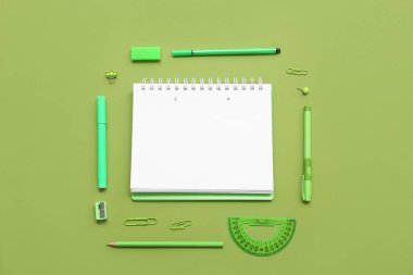Yeşil arka planda defter ve keçeli kalemler. Üst görünüm