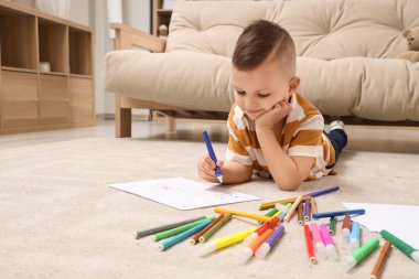 Evinde yerde keçeli kalemlerle çizen sevimli küçük çocuk.