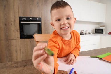 Mutfaktaki masasında keçeli kalemlerle çizen sevimli küçük çocuk.