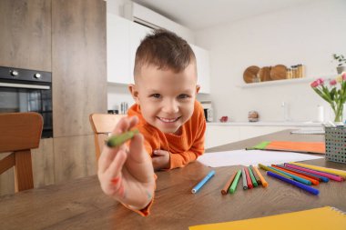 Mutfaktaki masasında keçeli kalemlerle çizen sevimli küçük çocuk.