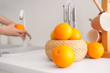 Hasır sepetin yanında turuncu yıkayan kadın elleri beyaz stil mutfaklarında narenciye ile