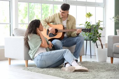 Mutlu genç çift evde gitar çalıyor.