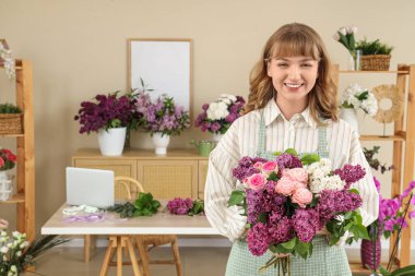 Çiçekçide elinde leylaklarla güzel bir buket tutan kadın çiçekçi.