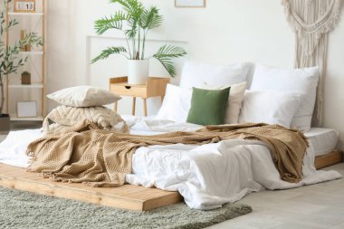 Yatak odasının içinde yumuşak yastıklı ve buruşuk battaniyeli rahat bir yatak.