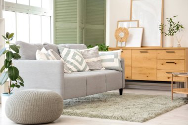 Oturma odasının içinde kanepe, çekmece ve yeşil katlanır ekran var.