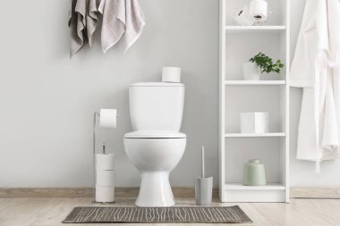 Tuvalet, raf ünitesi, bornoz ve havlular tuvalette.