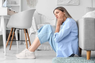 Evde diş ağrısı çeken genç bir kadın.