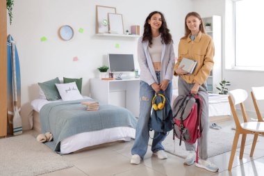 Yurt odasında sırt çantalı kız öğrenciler.