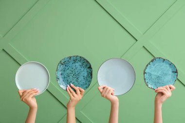 Yeşil arkaplanda boş tabakları tutan eller