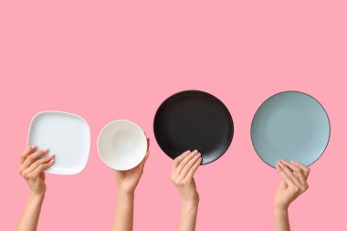 Pembe arka planda boş tabakları tutan eller