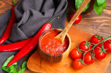 Ahşap arka planda fesleğen ve kırmızı biberli domates sosu.