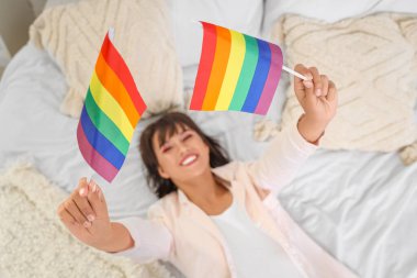 Yatak odasında yatağında LGBT bayrakları olan güzel genç bir kadın.