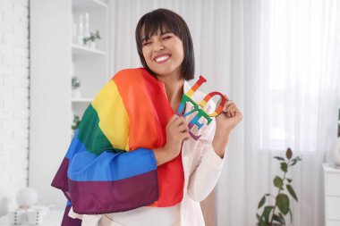 Yatak odasında LGBT bayrağı ve kelime aşkı olan güzel genç bir kadın.