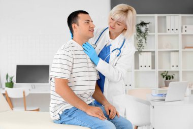 Kadın endokrinolog klinikteki kanepede tiroit bezini inceliyor.