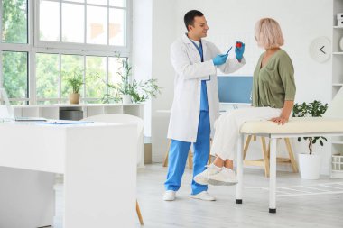 Erkek endokrinolog klinikte yetişkin kadın tiroid bezi modeli gösteriyor.