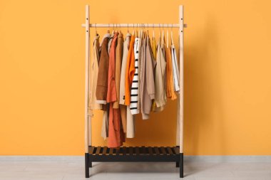 Sarı duvarın yanında sonbahar kıyafetleri asılı.