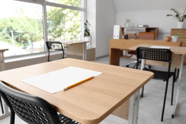 Modern okulda sınav için hazırlanmış kağıt ve kalemle dolu bir masa. Yakın çekim.