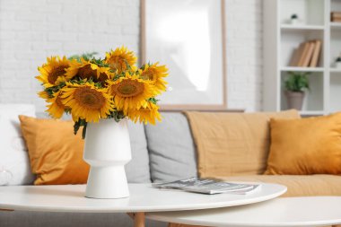 Sehpanın üstünde vazo ve ayçiçekleri olan şık bir oturma odası. Yakın çekim.
