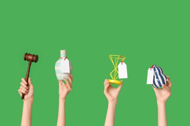 Açık arttırma tokmağı ve yeşil arka planda antika vazoları olan kadın eller.