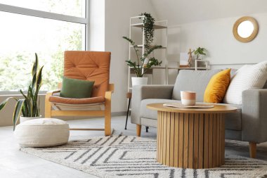 Ayna, gri kanepe ve koltuklu aydınlık oturma odasının içi.