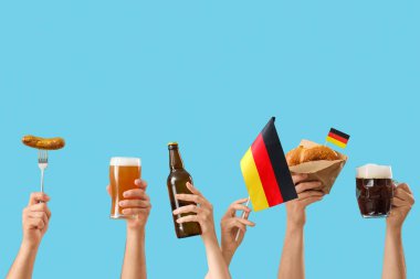 Soğuk bira bardakları, Alman bayrakları ve mavi arka planda geleneksel atıştırmalıklarla dolu bir sürü el. Ekim Festivali Kutlaması