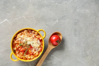 Bir kase peynirli makarna ve gri arka planda kekik.