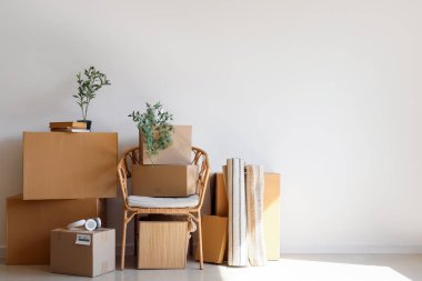 Kol sandalyesi, karton kutular ve odanın ışık duvarının yanındaki şeyler.