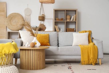 Oturma odasının içinde gri kanepe ve sehpanın üzerinde pampalar var.