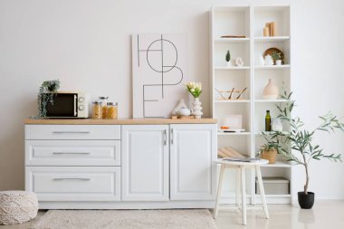 Beyaz tezgah, mikrodalga fırın, raf ünitesi ve mutfak içi resim.