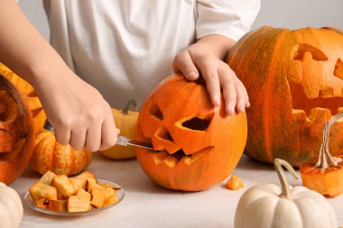 Bıçaklı kadın beyaz arka planda Cadılar Bayramı için farklı balkabakları oyuyor.