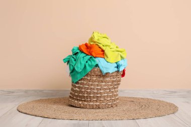 Bej duvarın yanında kirli giysileri olan hasır sepet.