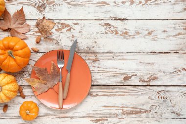 Taze balkabaklarıyla, badem fıstıklarıyla ve beyaz ahşap arka planda sonbahar yapraklarıyla güzel bir masa.