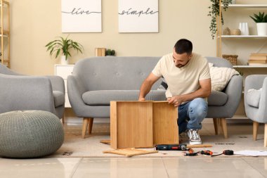 Evdeki çekmecede ahşap masa montajı yapan genç adam.