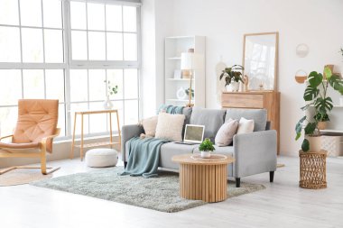 Koltukta, koltukta ve bitkilerde dizüstü bilgisayarı olan bir oturma odası.