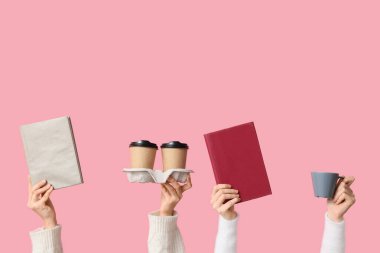 Pembe arka planda kitap ve kahve fincanları olan kadın elleri.