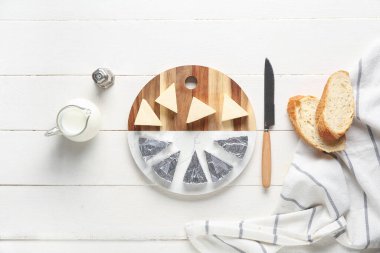 Hafif ahşap zemin üzerinde lezzetli işlenmiş peynir, ekmek, süt ve bıçak üçgenleri ile kompozisyon