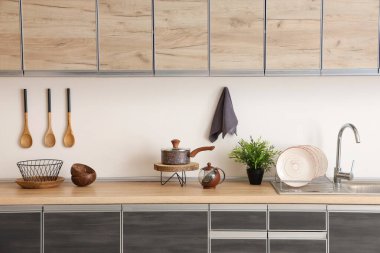 Mutfaktaki mutfak tezgahında saksı ve çatal bıçak var.