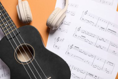 Ukulele, modern kulaklıklar ve renkli arka plan notaları, yakın plan