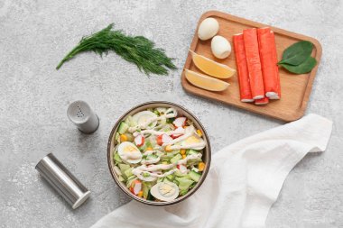 Yengeç saplı bir kase salata, buzdağı yaprakları, mısır, salatalık ve bıldırcın yumurtası gri grunge arka planda.