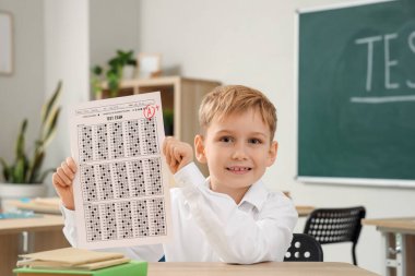 Sınıftaki test sonuçlarıyla sevimli bir okul çocuğu.