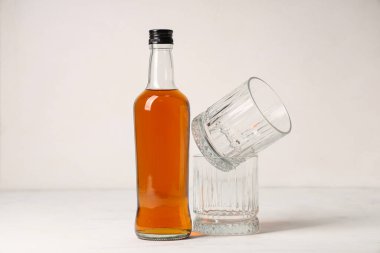 Beyaz arka planda bir şişe rom ve bardak.