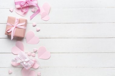 Beyaz ahşap arka planda pembe kalpleri olan hediye kutuları. Sevgililer Günü kutlaması