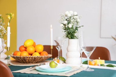 Tabakta narenciye ve vazoda çiçekler olan güzel bir masa. Yakın çekim.